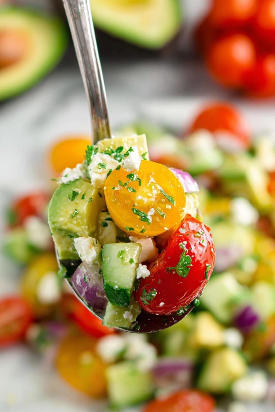 The image shows a close-up of a spoon holding a colorful salad with three main layers: small red cherry tomato halves, bright yellow cherry tomato halves, and chunks of light green avocado mixed with white feta cheese pieces and small bits of dark green parsley. The salad also includes small pieces of cucumber and red onion, adding pops of pale green and deep purple. The background is slightly blurred but shows a white marbled surface with more of the salad and whole cherry tomatoes, and a halved avocado. The overall look is fresh and vibrant, with different textures from soft avocado to firm tomatoes and crumbly cheese. Photo taken with an iphone --ar 2:3 --v 7