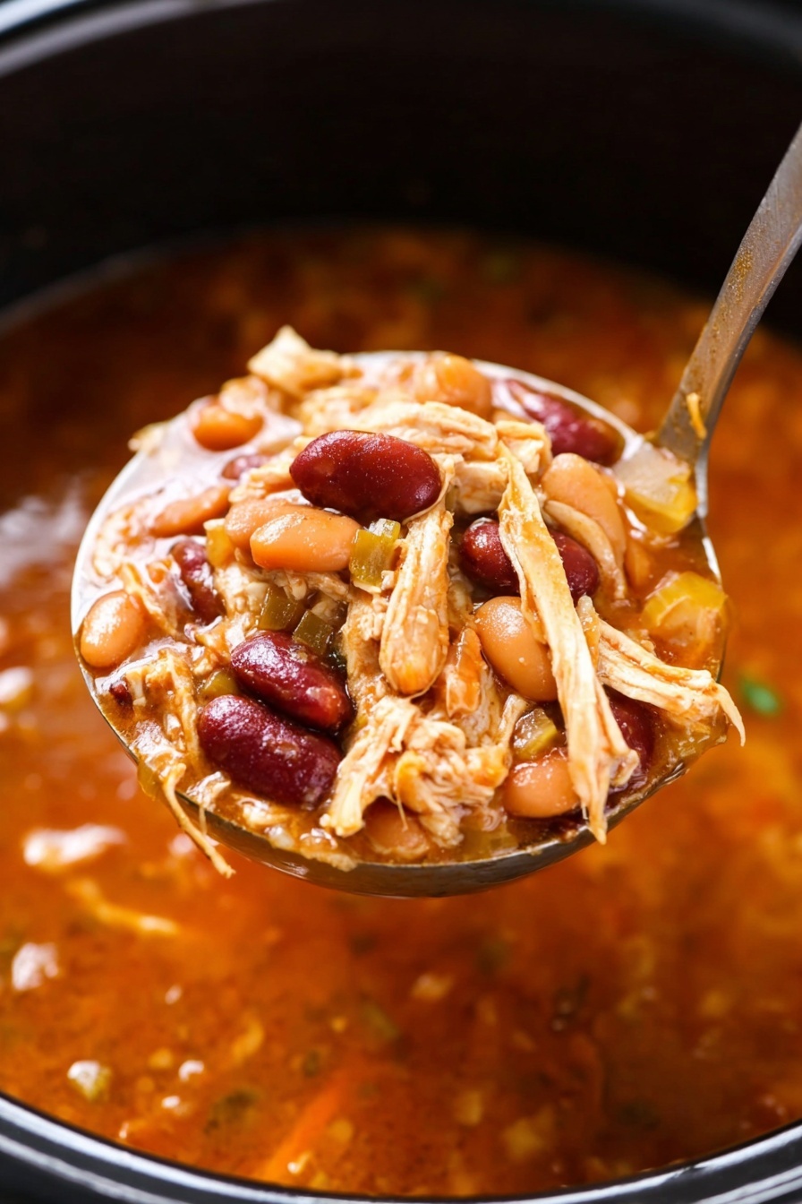 A large ladle holds a close-up scoop of thick stew, showing a rich orange-red broth base mixed with visible textures of shredded light brown chicken, reddish kidney beans, orange pinto beans, and small chopped pieces of yellowish onion; the ladle is inside a dark pot filled with more of the same stew. The background is a white marbled texture. photo taken with an iphone --ar 2:3 --v 7