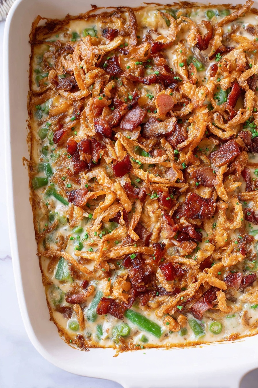 A casserole dish filled with a one-layer baked mixture showing visible green vegetable pieces and creamy light tan sauce underneath, topped with crispy brown fried onion strings and scattered reddish-brown cooked bacon bits, all giving a crunchy and rich texture on top. The casserole is in a white rectangular dish placed on a white marbled surface. The edges of the dish show a slightly browned crust where the sauce and toppings meet photo taken with an iphone --ar 2:3 --v 7