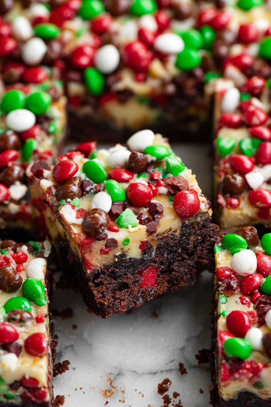 The image shows several thick square brownies with three clear layers. The bottom layer is a dark, rich chocolate cake base with a dense, moist texture. The middle layer is a creamy white topping that looks soft and smooth. The top layer is full of small, round candies in bright red, green, white, and brown colors, scattered all over, giving a shiny and colorful look. The brownies are placed close together on a white marbled surface with some crumbs around. One square in the middle is pushed slightly up and forward, showing the thick layers and the vibrant candy topping clearly. photo taken with an iphone --ar 2:3 --v 7