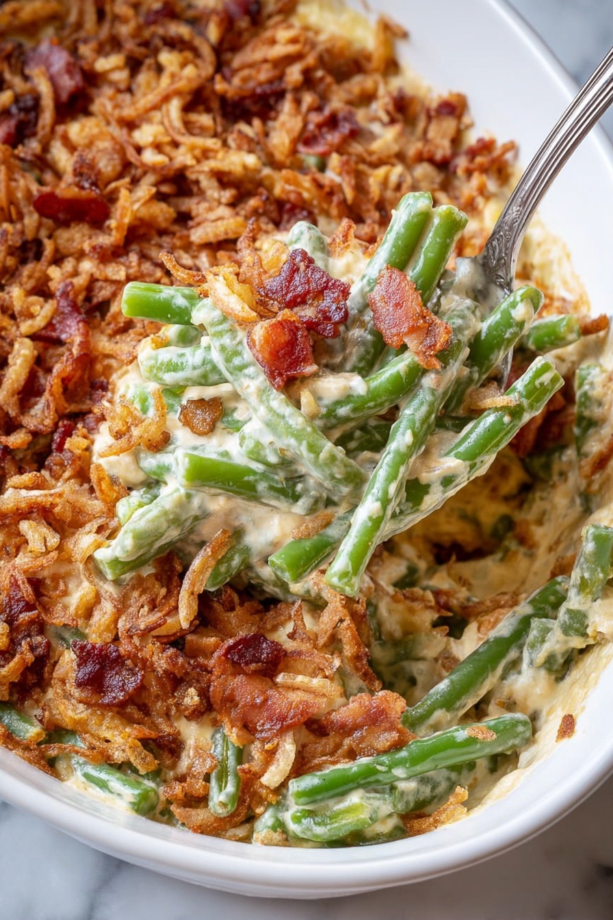 The dish is a creamy casserole with three main layers visible: the bottom layer is a rich, creamy cheese sauce mixed with soft green beans showing some texture; the middle layer contains bright green, slightly firm green beans scattered throughout; the top layer is a crunchy, golden-brown topping made from crispy fried onions and small bits of reddish-brown bacon. The casserole is served in a white oval dish on a white marbled surface, and a silver serving spoon holds up a scoop showing all the layers clearly. Photo taken with an iphone --ar 2:3 --v 7