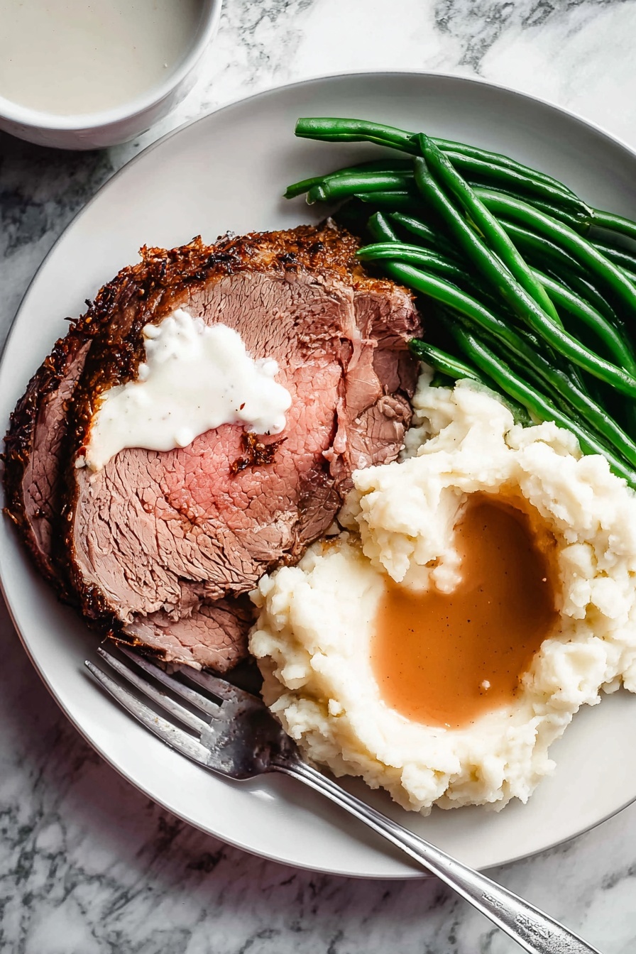 The image shows a white plate with three main layers of food. On the left side, there is a large slice of roasted meat with a dark brown crust and a pink inside, topped with a dollop of white creamy sauce. Next to the meat are bright green cooked green beans lying in a neat pile. Below the green beans and meat, there is a mound of white mashed potatoes with a smooth texture, topped with light brown gravy pooling in the center. A silver fork lies on the plate touching the mashed potatoes, and the plate is set on a white marbled surface with a small bowl of white sauce visible in the top left corner. Photo taken with an iphone --ar 2:3 --v 7