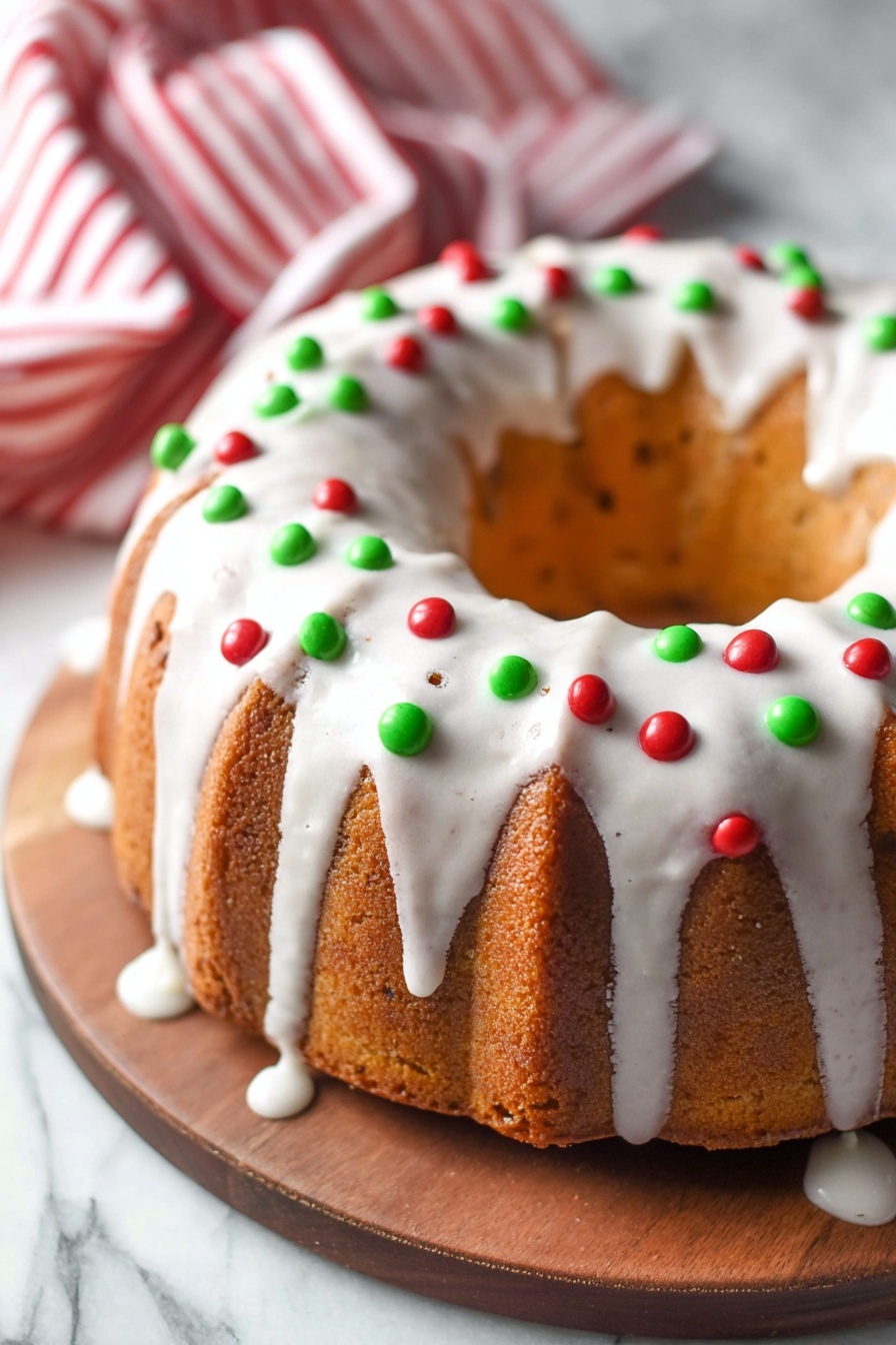 A round bundt cake sits on a wooden board placed on a white marbled surface. The cake is golden brown with soft ridges around it. It has a thick layer of white icing dripping smoothly down the sides. Small round red and green candy decorations are scattered evenly over the icing, adding bright pops of color. A red and white striped cloth is slightly visible in the upper left corner. photo taken with an iphone --ar 2:3 --v 7