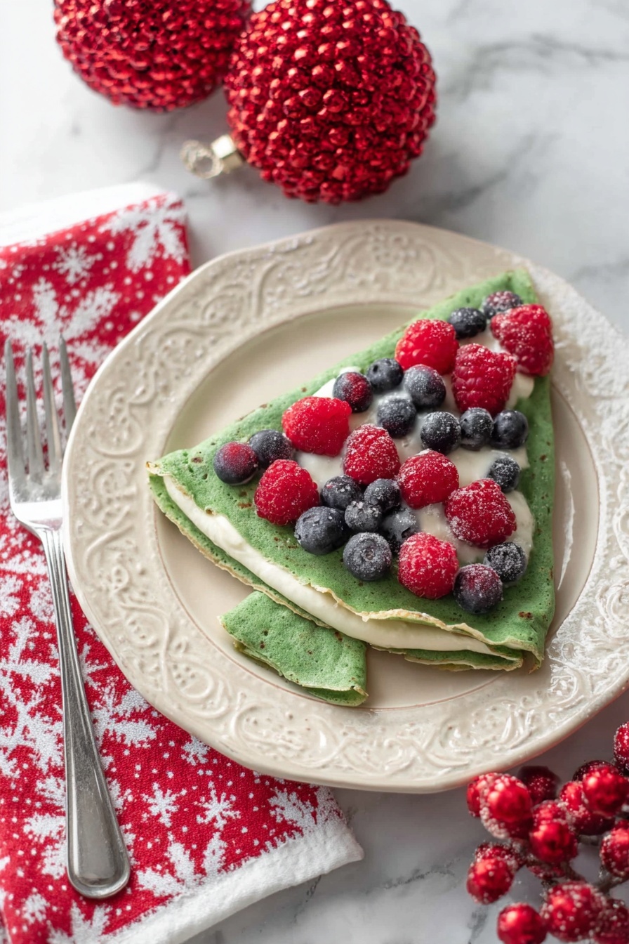 A white plate with decorative edges holds three folded green crepes layered with white cream. Each crepe is folded into a triangle, revealing smooth cream peeking out between the folds. On top of the crepes, there is a line of alternating fresh raspberries and blueberries, adding red and blue accents. The plate is on a white marbled surface, with two red decorative berry cones and a white cloth with red tree patterns blurred in the background. Photo taken with an iphone --ar 2:3 --v 7