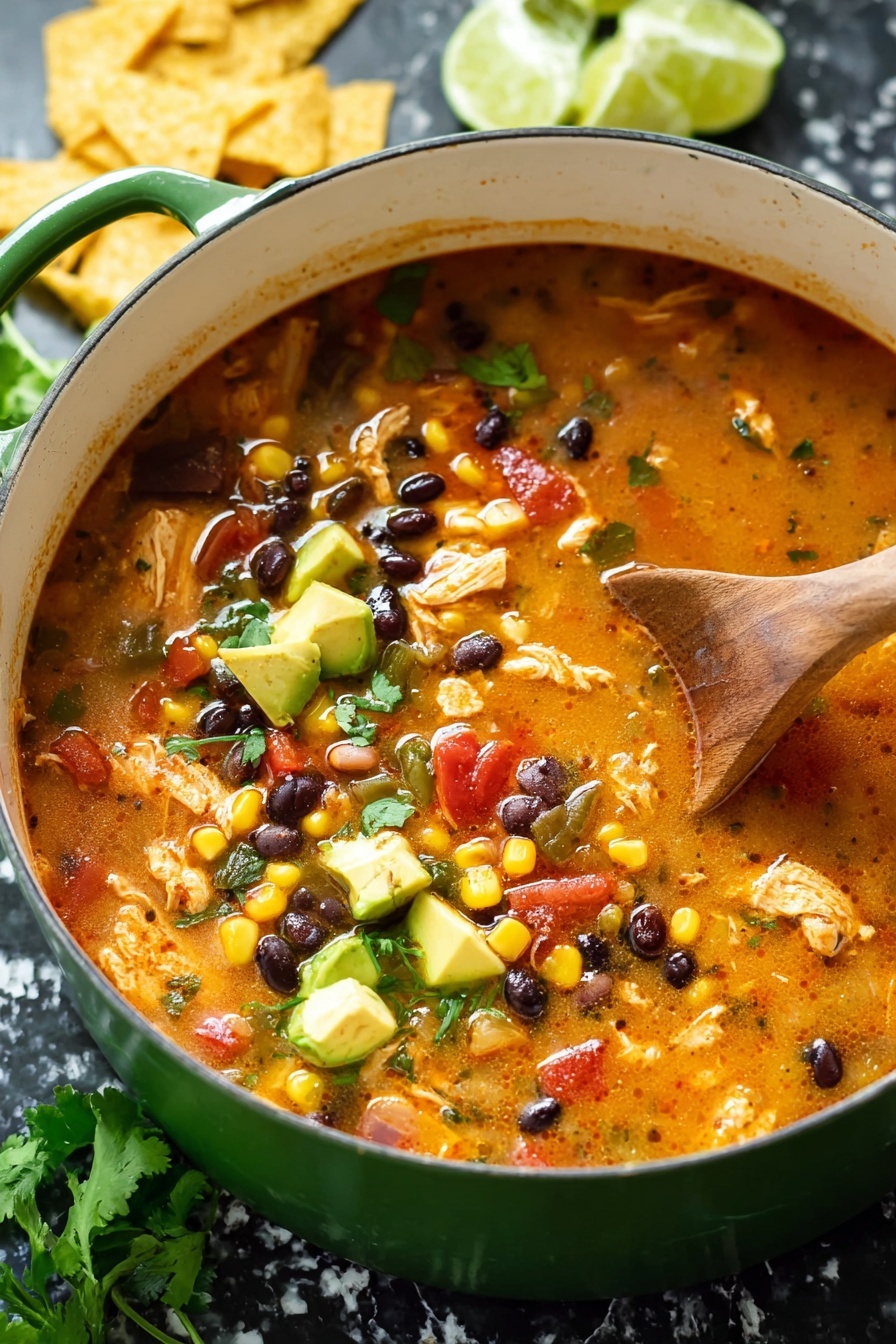 A close-up view of a thick soup in a green pot with a white inside, filled with layers of yellow corn kernels, black beans, reddish diced tomatoes, and green bell peppers, all floating in a rich orange broth. The soup also shows pieces of light brown cooked chicken and small onion bits, with some fresh green cilantro leaves on the side and a few slices of fresh green avocado resting on the right edge. A wooden spoon is partially dipped into the soup from the top right, stirring the mix. In the background, there are wedges of lime and some yellow tortilla chips on a white marbled surface. Photo taken with an iphone --ar 2:3 --v 7