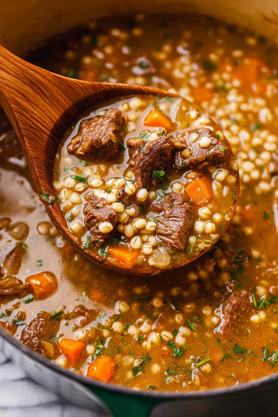 A close-up of a thick stew with chunks of dark brown meat, small round barley grains, and pieces of orange carrot floating in a rich, light brown broth with visible green herbs. The stew fills a large pot with a dark green edge, and a wooden spoon is scooping a hearty portion showing the mix of meat, grains, carrots, and herbs clearly. The texture looks creamy but chunky, with a shiny surface on the broth. The background surface is white with a marbled texture. photo taken with an iphone --ar 2:3 --v 7