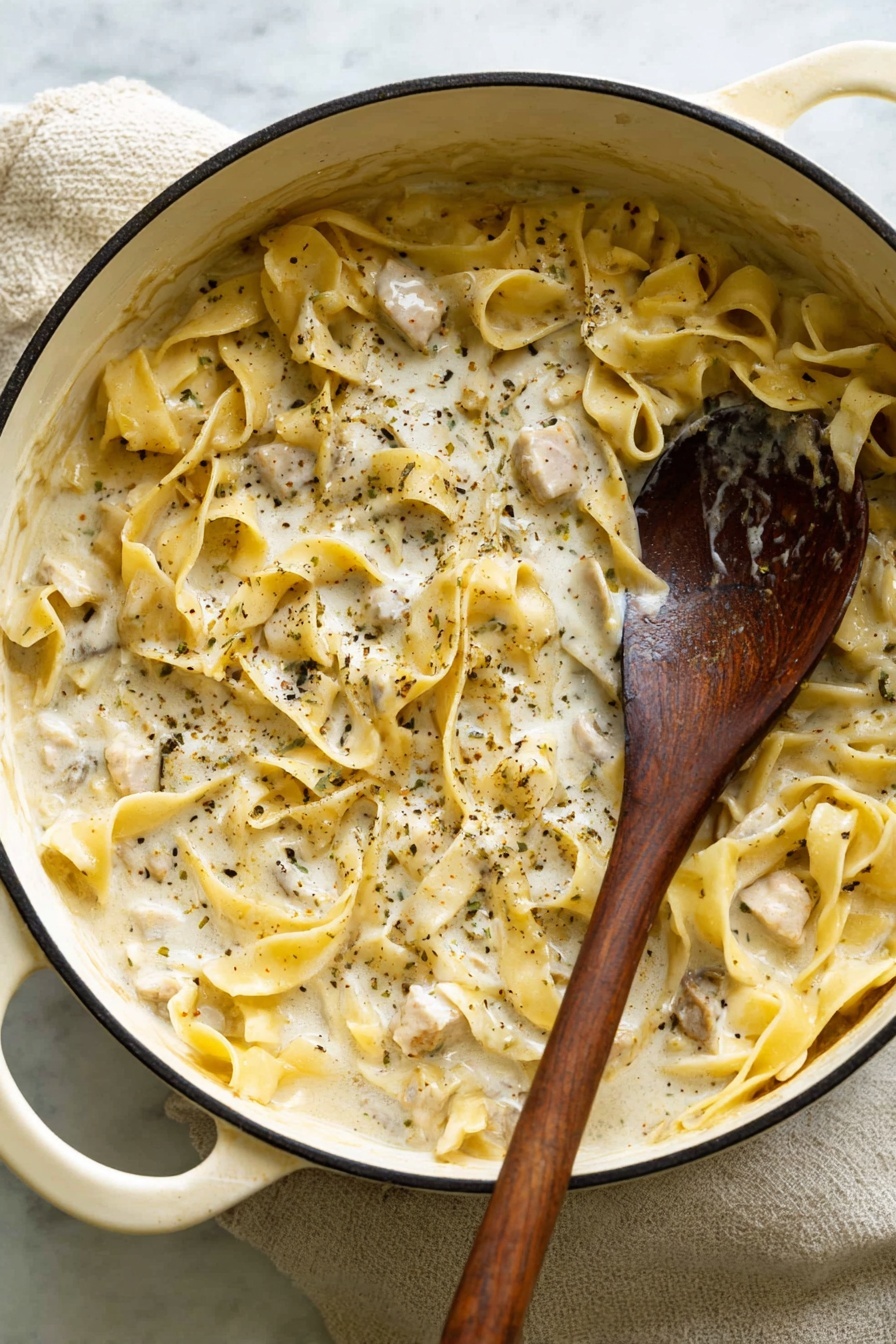 A white pot filled with creamy sauce coated wide flat pasta noodles mixed with small chunks of light-colored meat, sprinkled with black pepper and herbs throughout; a dark wooden spoon inside the pot scoops the mixture on the right side, all set on a white marbled surface with a light cloth underneath. photo taken with an iphone --ar 2:3 --v 7